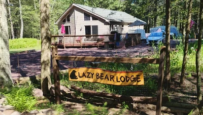 Hanging wooden Lazy Bear Lodge property sign with a black bear silhouette