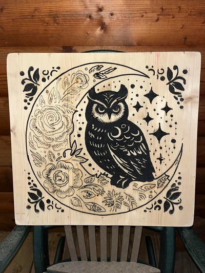 Carved owl perched on a crescent moon surrounded by flowers and stars