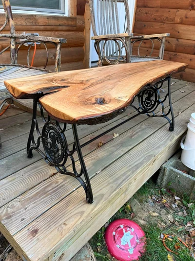 Live-edge hardwood table with natural bark edge on a handcrafted cast-iron base